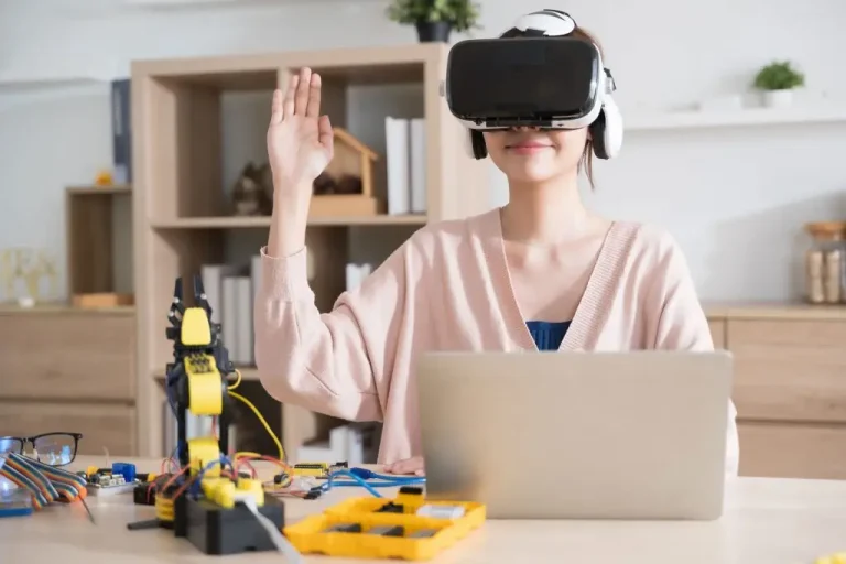 The Asian woman engineer programmer wears a VR headset to learn how to programme a robot arm using artificial intelligence.